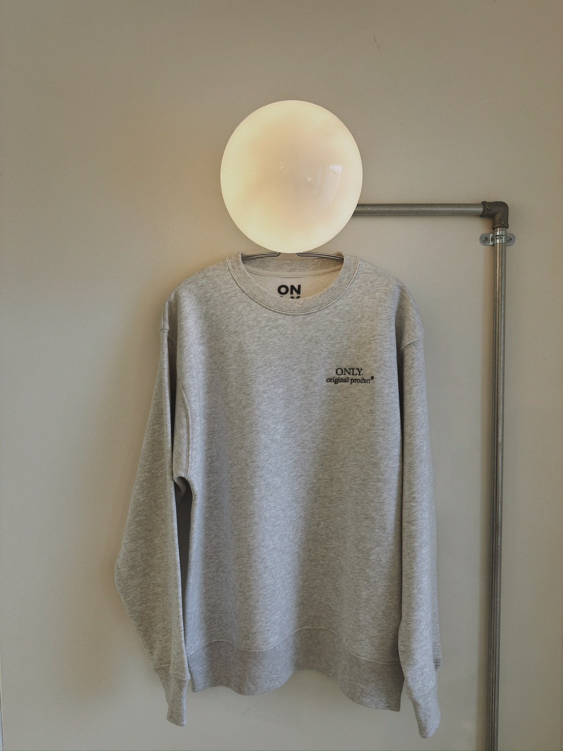 照明にかけられたONLY.オリジナルスウェットシャツ