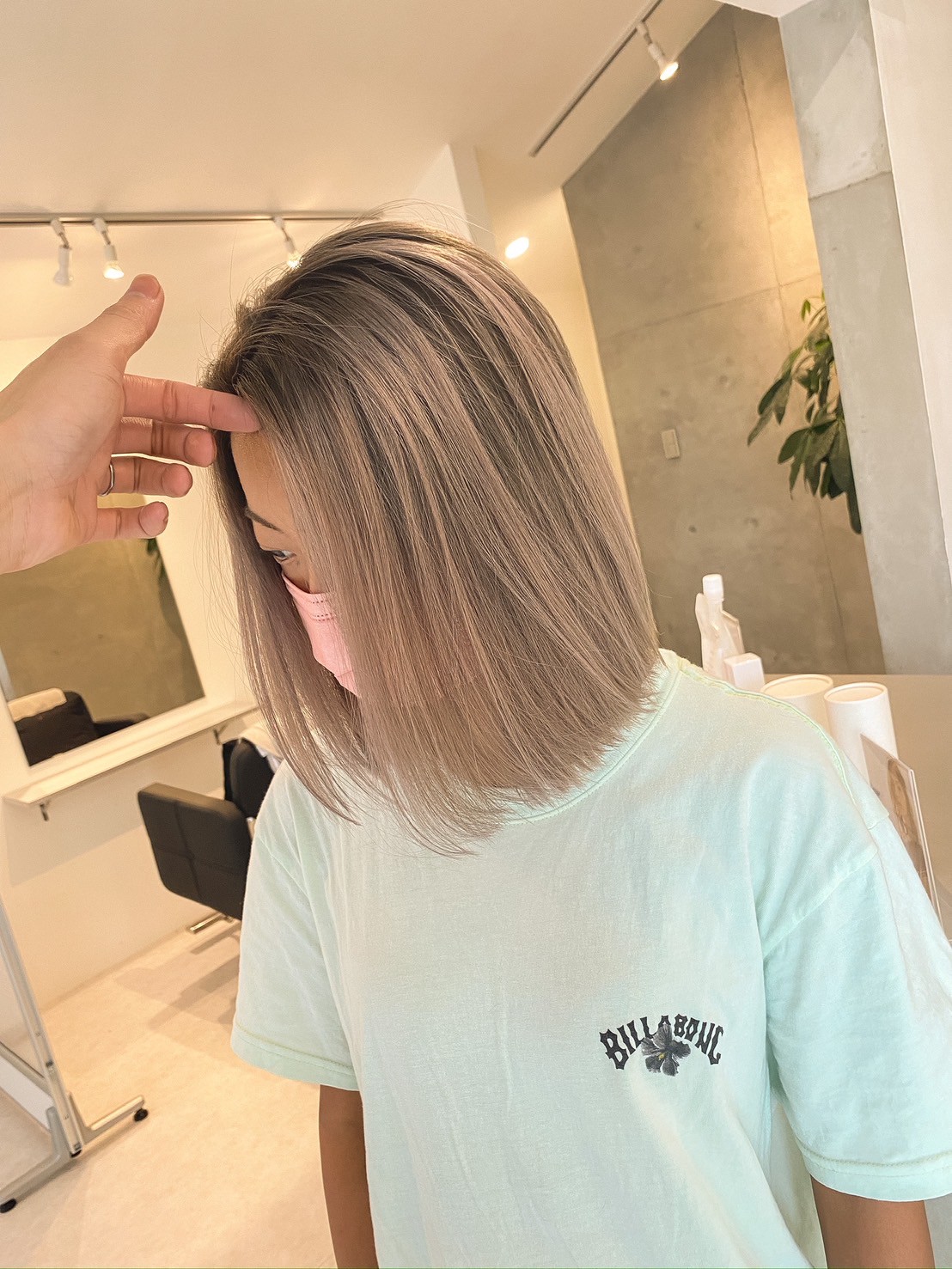 ピンクアッシュ系の艶やかストレートボブ（スタイリストの手、マスク姿）