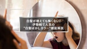 白髪を気にする女性が鏡を見つめる様子。伊勢崎で話題の白髪ぼかしカラーの魅力を伝えるイメージ。